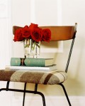 Una sedia vintage usata come tavolino per dei libri e un bel vasetto di rose rosse.