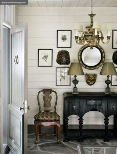Un ingresso classico, strutturato su un'unica parete: mobile con due lampade gemelle, specchio e seggiola.